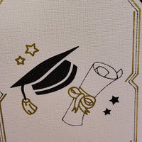Detailed view of black mortarboard and diploma illustration with gold ribbon and stars, printed on textured ivory card for a handmade finish.