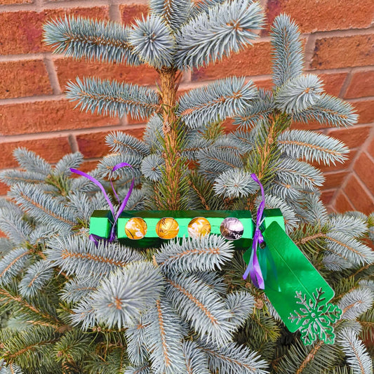 Personalised chocolate cracker gift hanging on a Christmas tree branch, decorated with colorful treats.