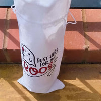 White Halloween wine bag holding a bottle with orange cap, ghost illustration and text "Just Here for the Boos", placed against brick steps.