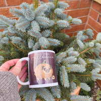 Close-up of Happy Halloween pug mug showing cute cartoon pug inside a pumpkin, with a small skull detail on a purple background.