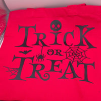 Red Halloween trick or treat tote bag with black spooky font, skull, spider, bat and cobweb design, perfect for kids to collect sweets.