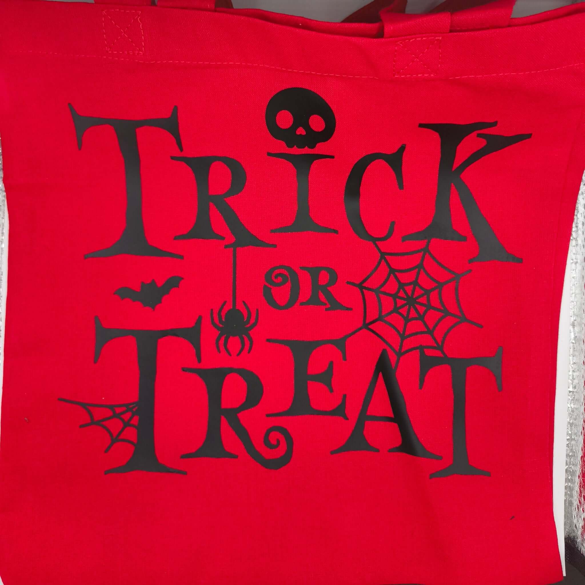 Halloween tote bag in bright red cotton with black spooky Trick or Treat design featuring spider, skull and bat details.