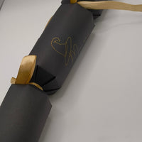 Handmade black cracker assembled with gold ribbon ties, featuring a witch hat “Mum” design in gold foil
