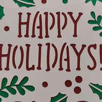 Close-up of handmade festive Happy Holidays card with red lettering and green backing.