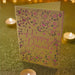 Handmade Happy Diwali greeting card with intricate pink floral cut-out design on gold cardstock, styled with festive fairy lights.
