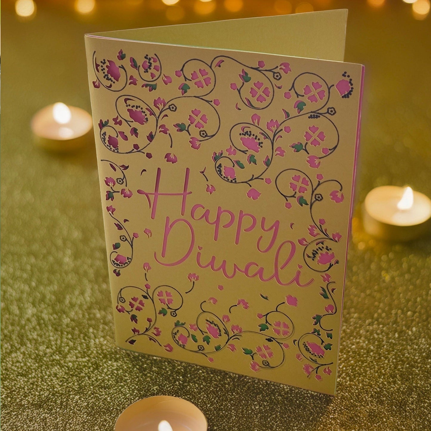Handmade Happy Diwali greeting card with intricate pink floral cut-out design on gold cardstock, styled with festive fairy lights.