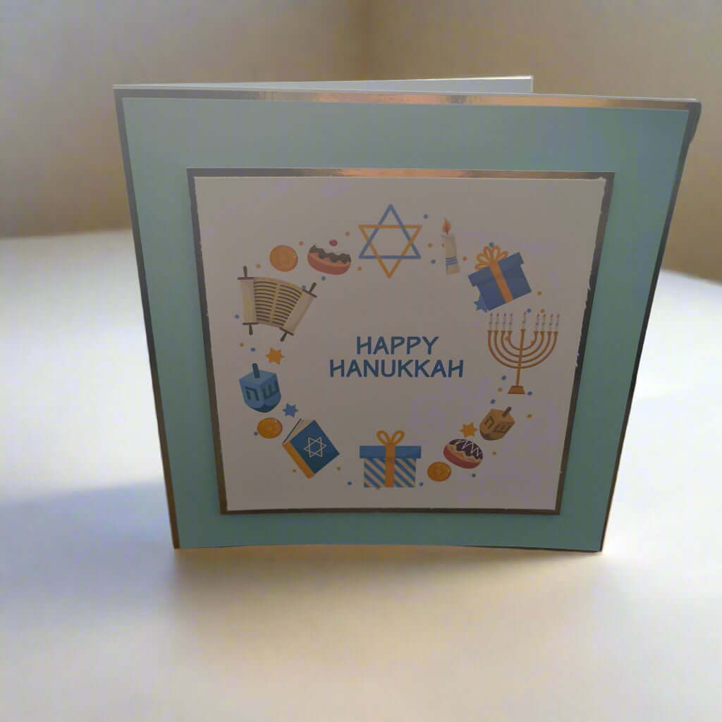 Handmade Happy Hanukkah card with Star of David and gift illustrations, photographed from a front-left angle on a white background — perfect Jewish holiday greeting.