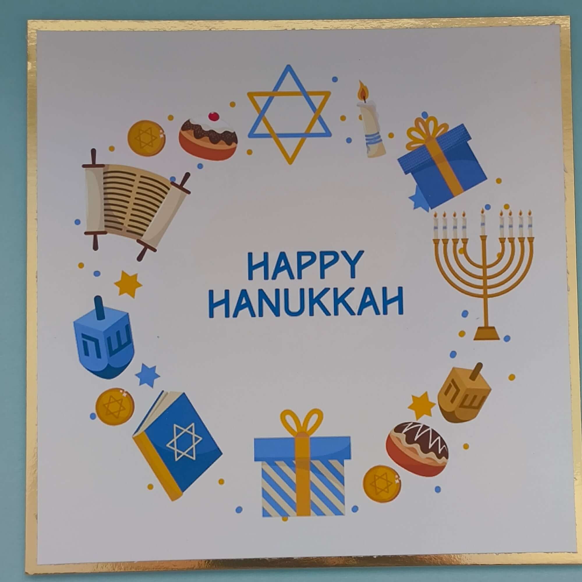 Flat lay close-up of a handmade Happy Hanukkah greeting card featuring a Star of David, menorah, dreidel, and festive icons — Jewish holiday card design.