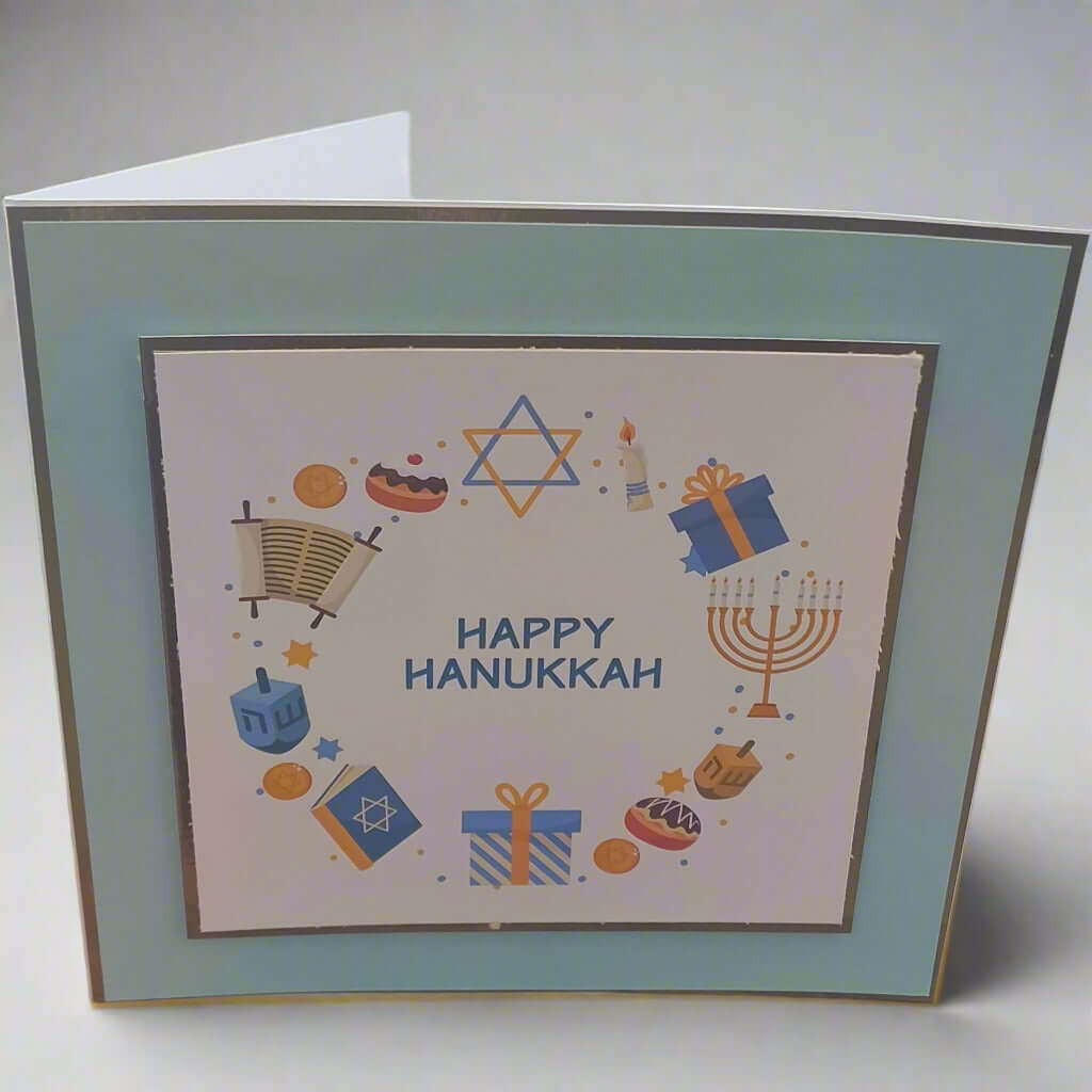 Handmade Happy Hanukkah card with Star of David and festive icons, photographed from a front-right angle on a light background — Jewish holiday greeting card.