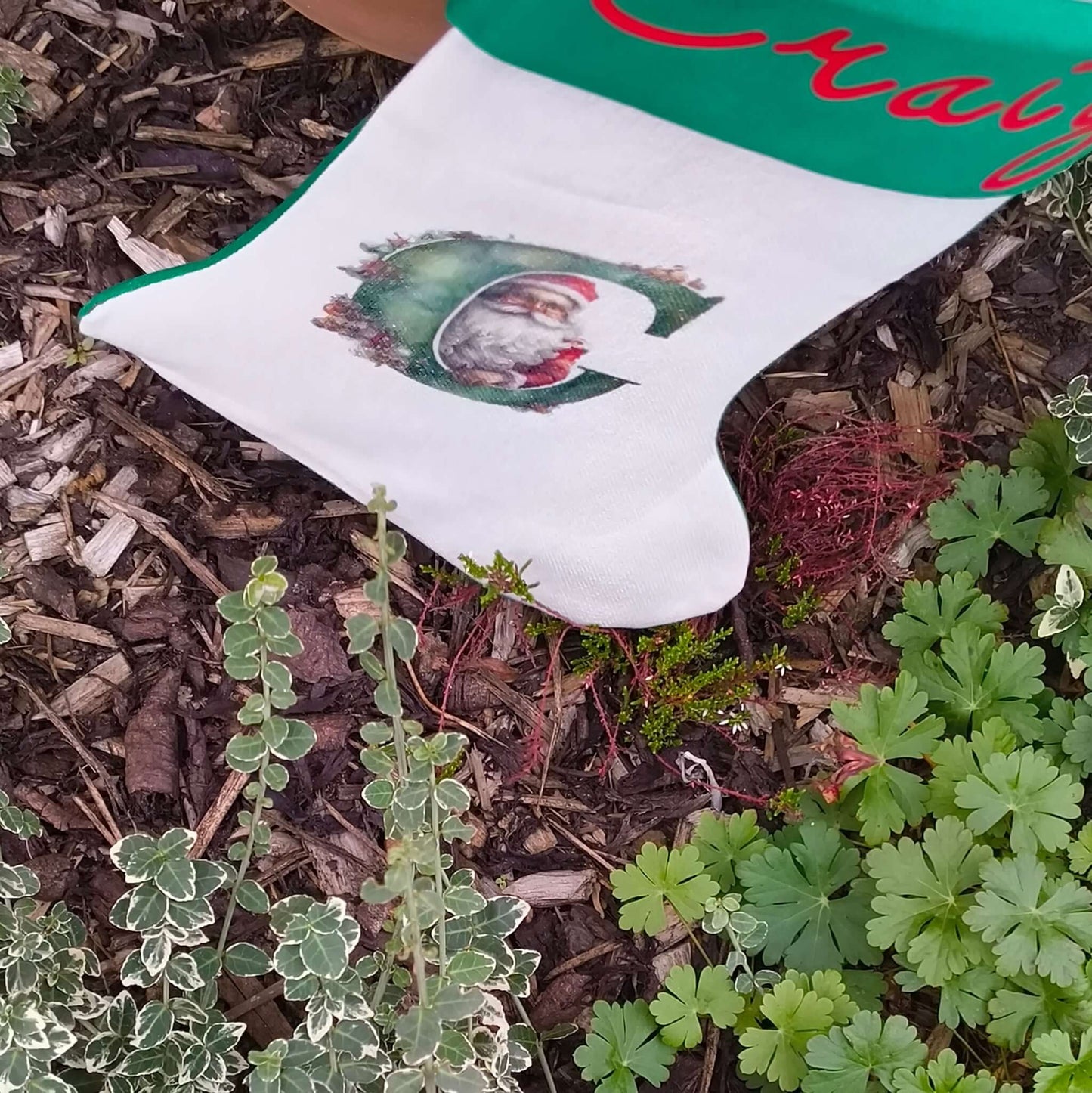 Personalised Vintage Santa Christmas Stocking with red script name and Santa illustration in a garden setting.