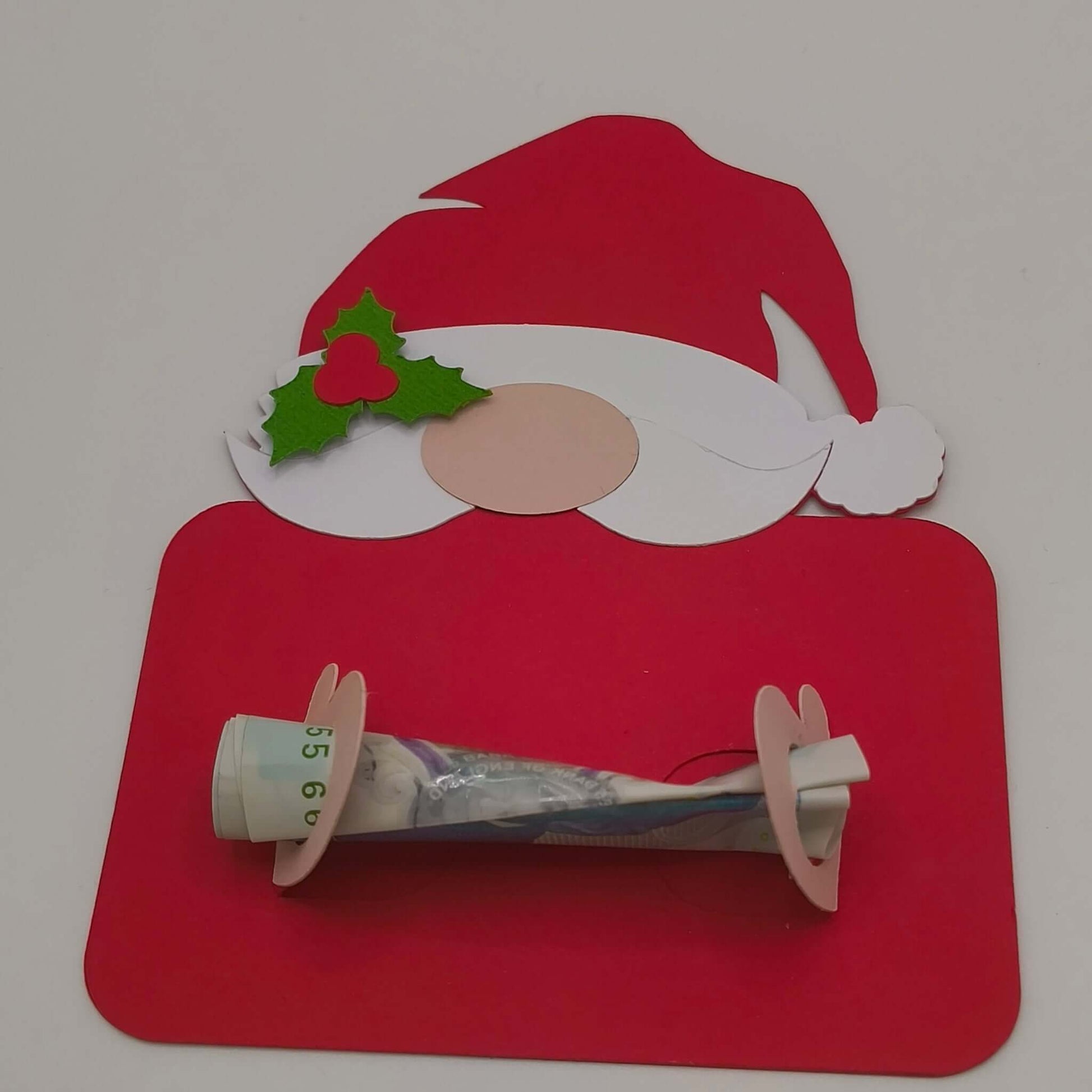 Festive handmade Santa money holder card in red with beard, holly, and nose, holding a rolled banknote securely across the centre.
