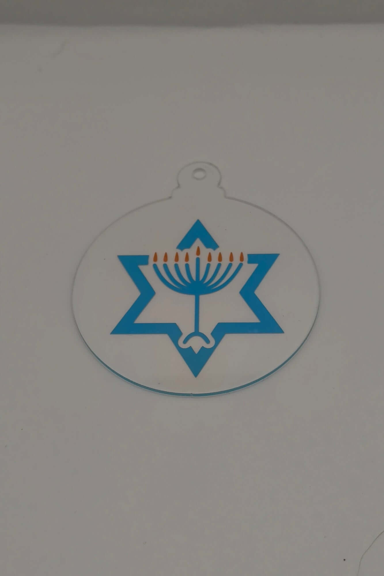 Clear acrylic Hanukkah ornament with a blue Star of David and gold menorah candles.