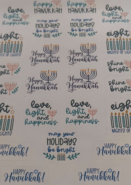 Flat lay image of assorted Hanukkah stickers featuring menorahs, candles, and festive phrases like “Happy Hanukkah” and “Love, Light, and Happiness,” arranged on a white background.