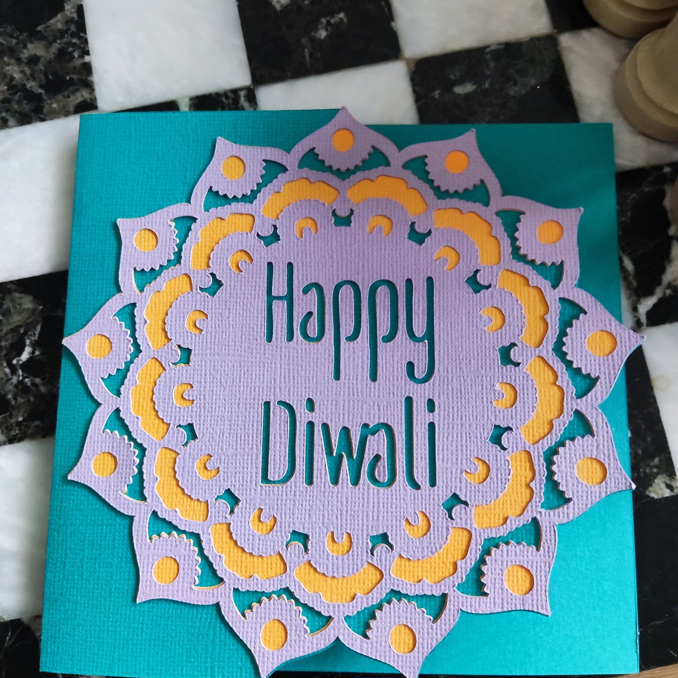 Overhead view of Diwali card highlighting the intricate mandala cut-out, textured cardstock, and bold colour contrast.