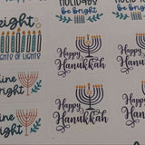Close-up of Hanukkah sticker sheet featuring festive messages like “Happy Hanukkah,” “Shine Bright,” and “Holidays Be Bright,” with menorah and candle illustrations on a white background.

