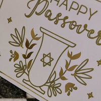 Close-up of the floral gold foil detailing around the goblet design. Textured cardstock with metallic shine captured clearly.