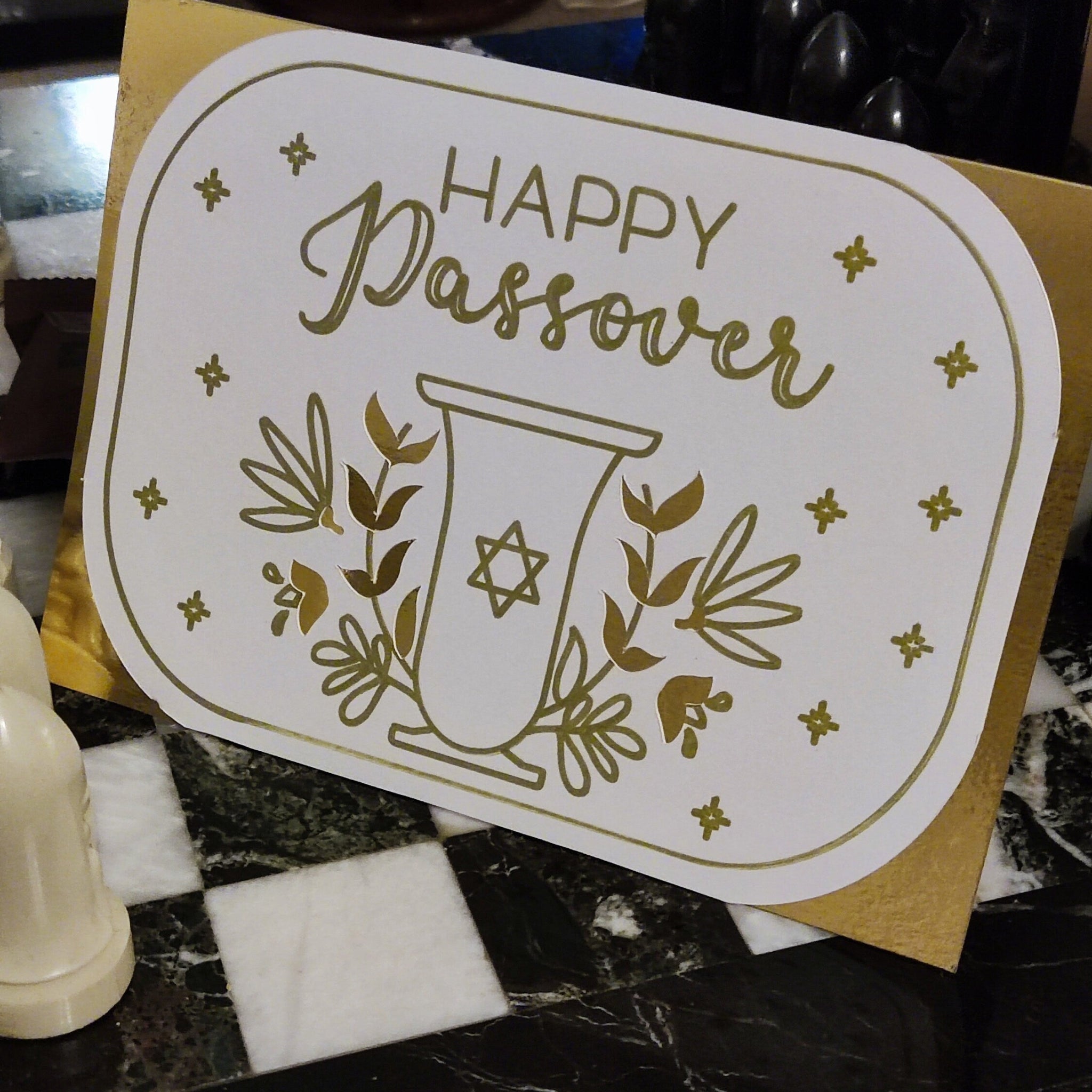 Elegant white card with gold foil “Happy Passover” design, featuring a Star of David goblet and floral motifs. Photographed upright to show full scale and shine.