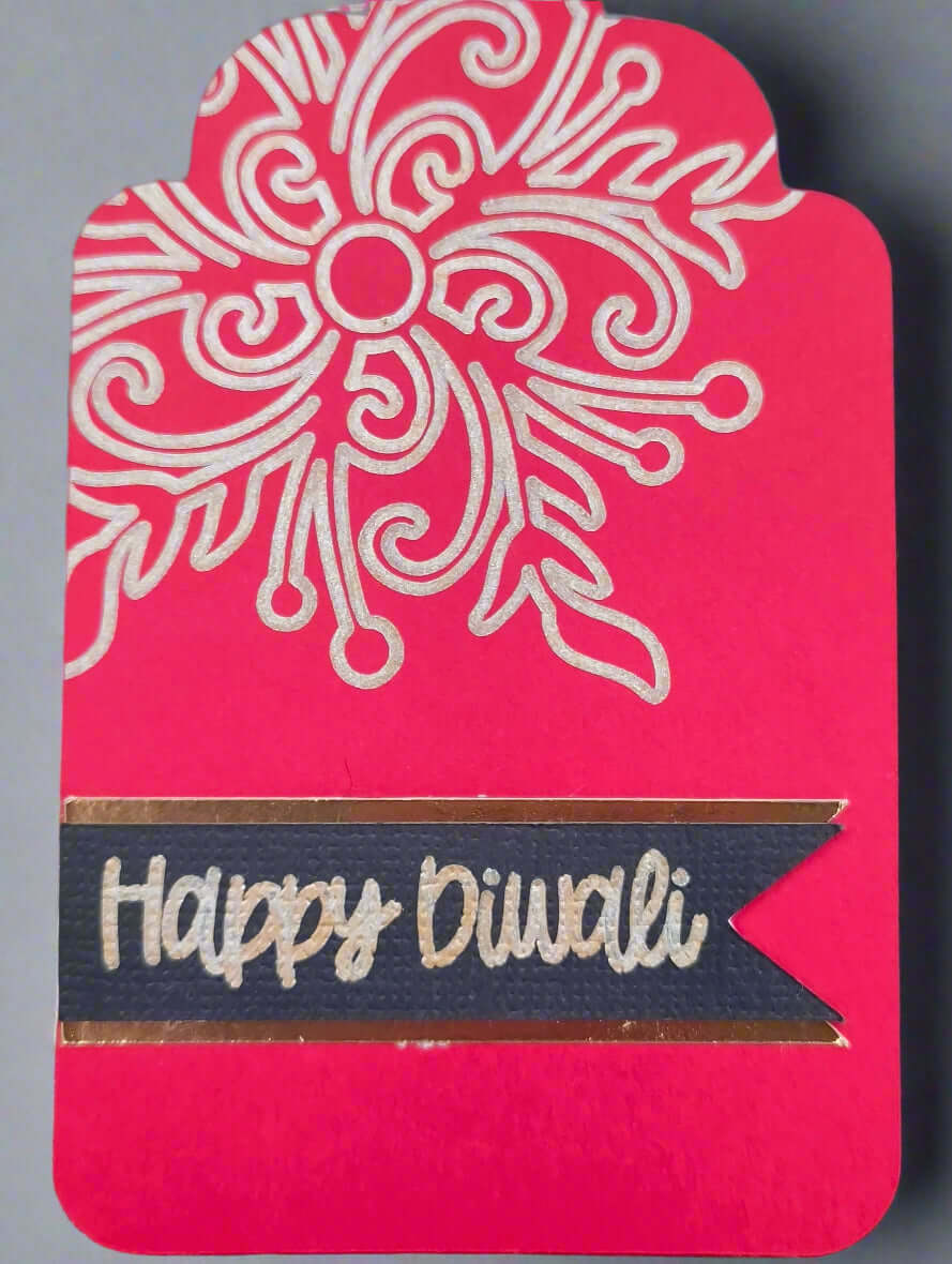 Close-up of black and gold Happy Diwali label on textured cardstock with elegant floral detail above