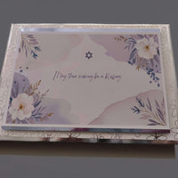 Jewish condolence card with Star of David and floral design, message reads 'May their memory be a blessing', shown with matching envelope