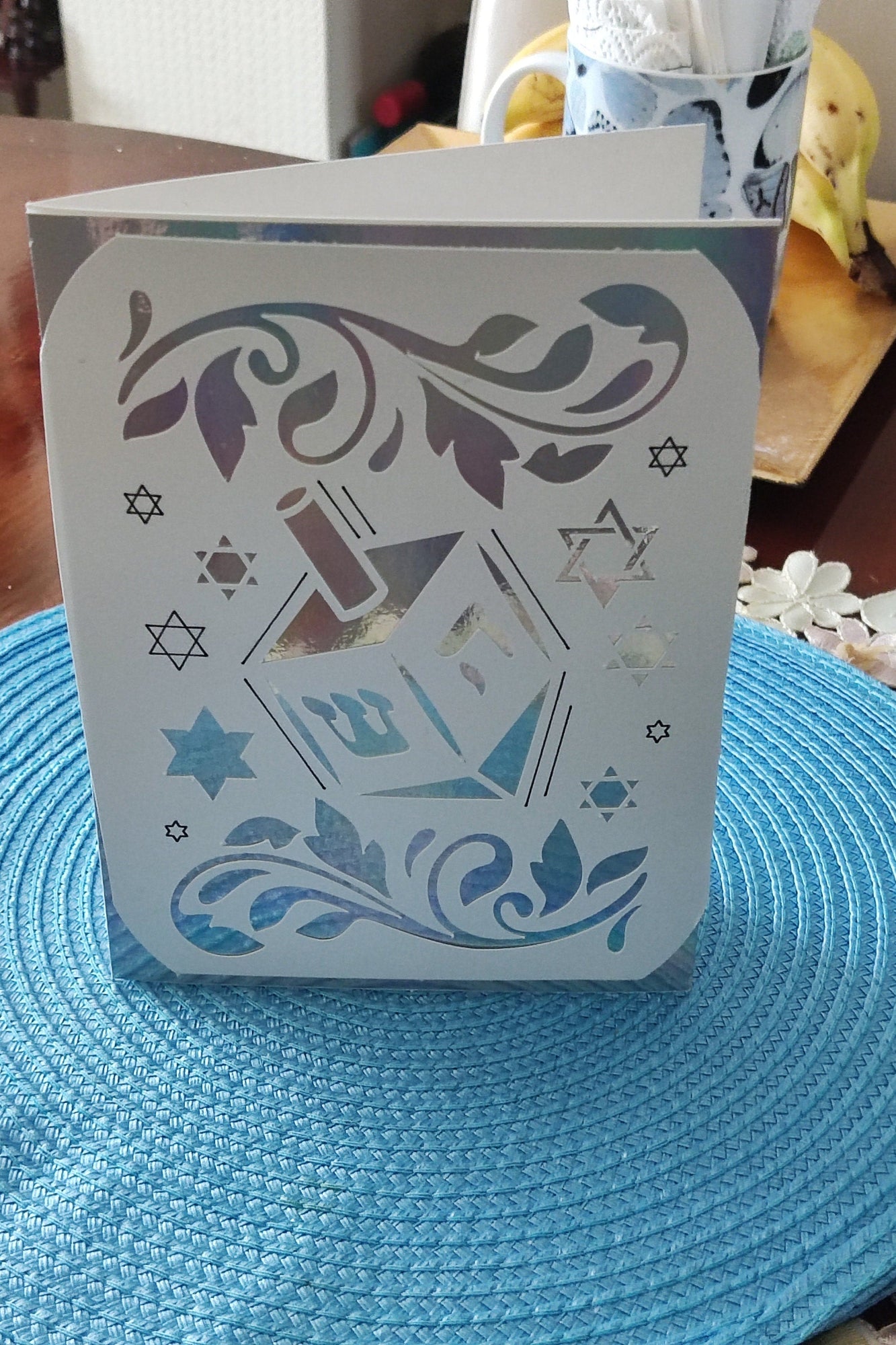 Jewish festival card with dreidel and floral cut-out pattern, holographic detail