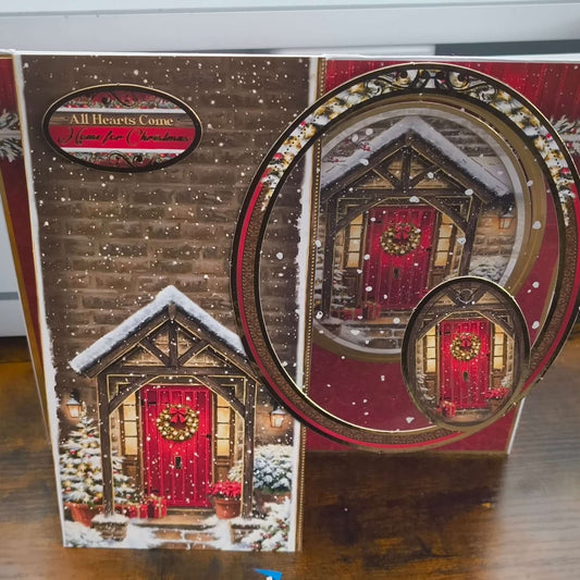 Side view of handmade Christmas card with layered oval topper showing red door, snow scene, and festive garland details.