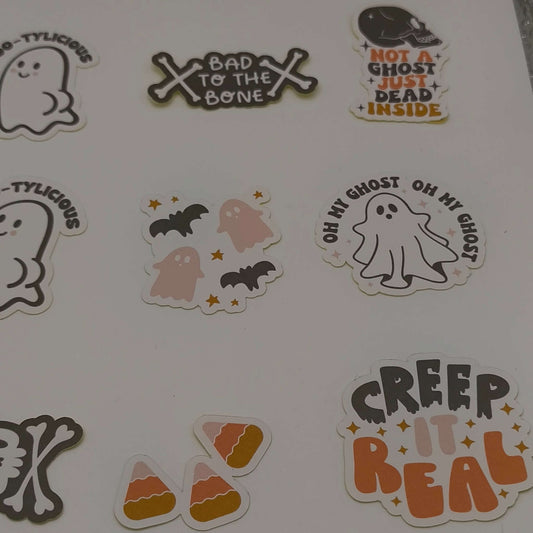 Assorted loose Halloween stickers including “Bad to the Bone”, “Not a Ghost Just Dead Inside”, candy corn, “Creep It Real”, and spooky ghost designs.