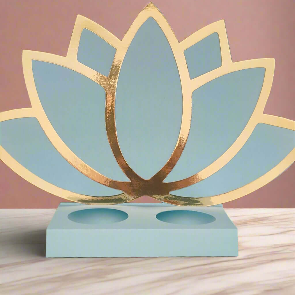 Front-facing image of a pastel blue and gold Diwali lotus sweet holder made from layered cardstock, placed on a marble surface with a soft blush pink background.