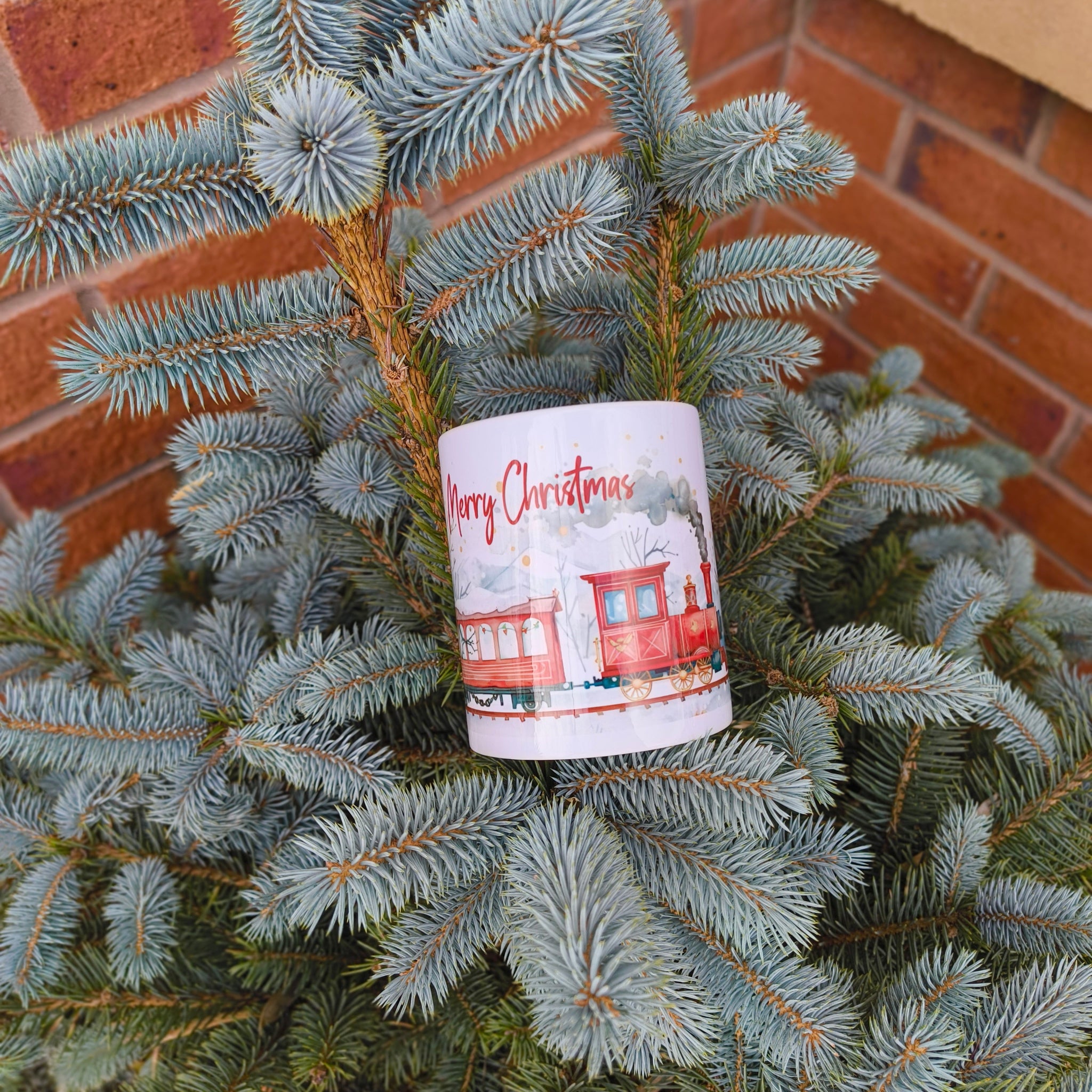 Merry Christmas ceramic mug with vintage train scene displayed on pine tree