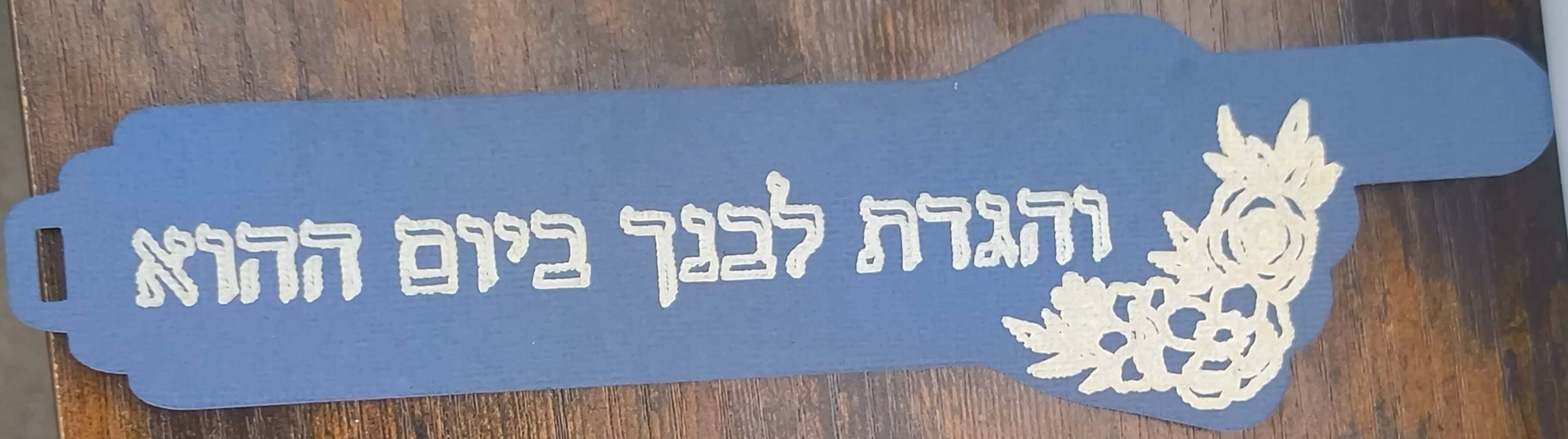 Blue handmade Passover bookmark featuring Hebrew text and floral design details.