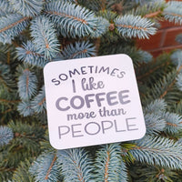 Funny coffee coaster gift with the phrase 'Sometimes I like coffee more than people' on a blue spruce background.
