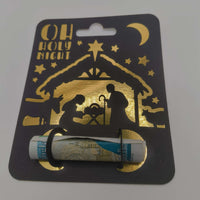 Black card money holder with gold nativity scene and “Oh Holy Night” text, holding a rolled banknote.