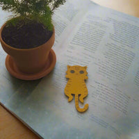 Flat lay of handmade orange cat bookmark on open book with plant in terracotta pot