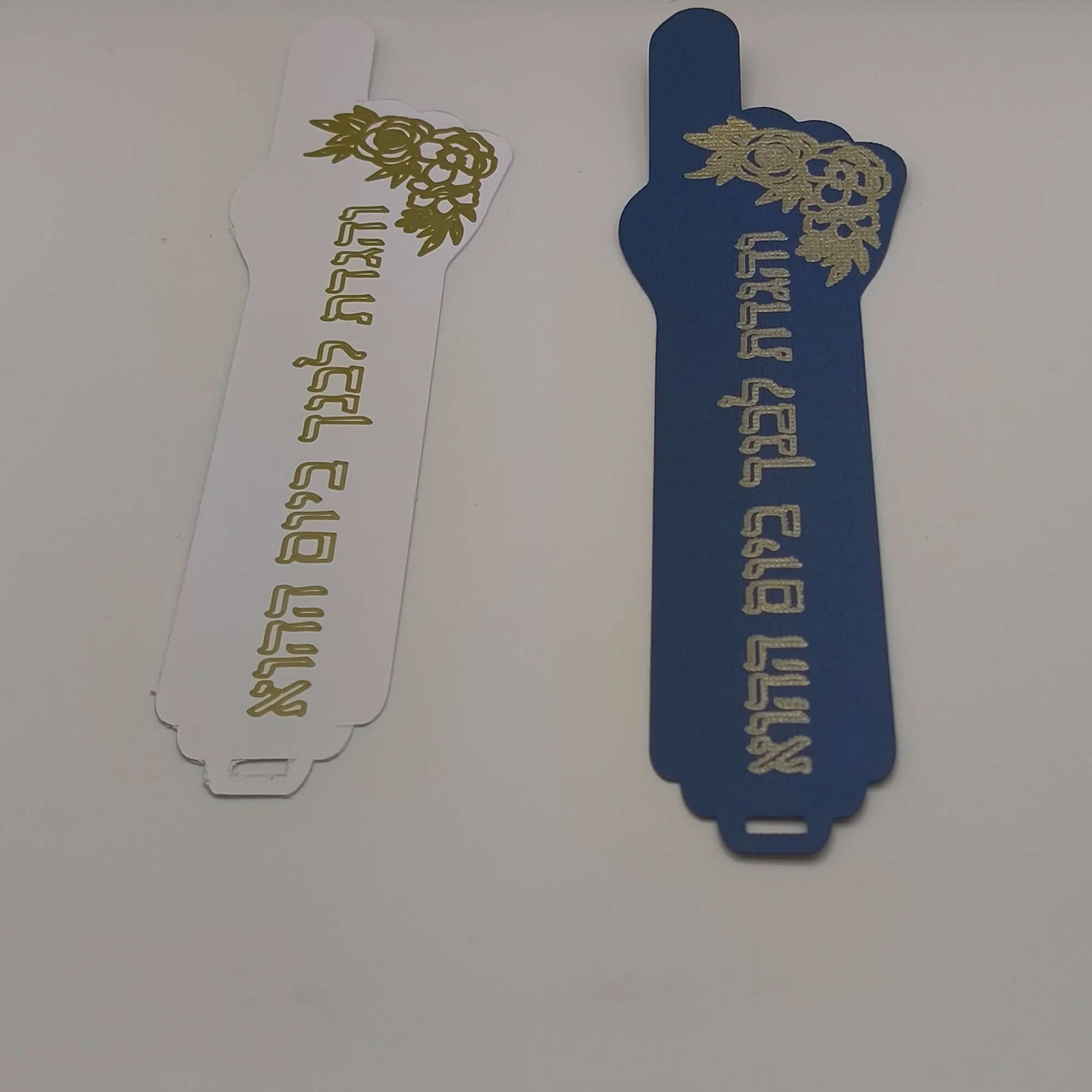 Handmade Passover bookmarks featuring Hebrew verse and intricate foil detail in white and navy blue.