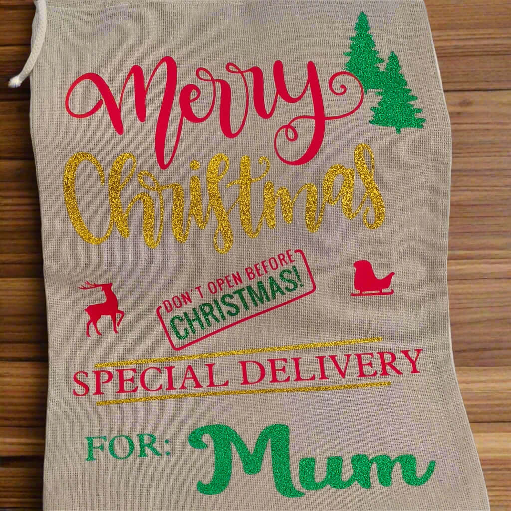 Personalised Christmas gift sack for Mum – hessian fabric with gold glitter “Christmas”, red festive icons, green vinyl name and trees, special delivery holiday design.