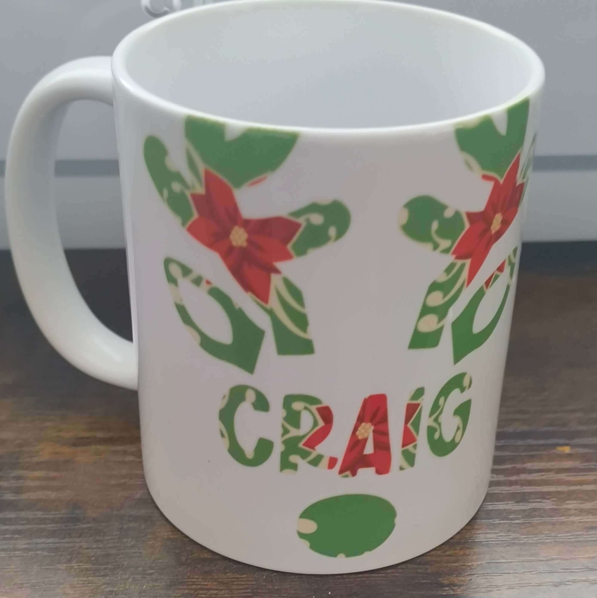 Personalised Christmas mug with Craig's name and festive poinsettia and holly design.