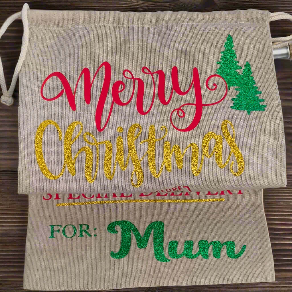 Personalised Merry Christmas gift sack for Mum – gold glitter text with red and green vinyl on rustic hessian fabric, festive tree design, perfect for holiday gifting.


