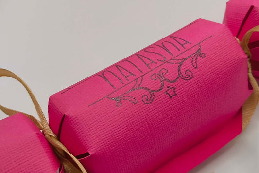Personalised birthday crackers in vibrant pink with gold ribbon, perfect for celebrations and custom gifts.