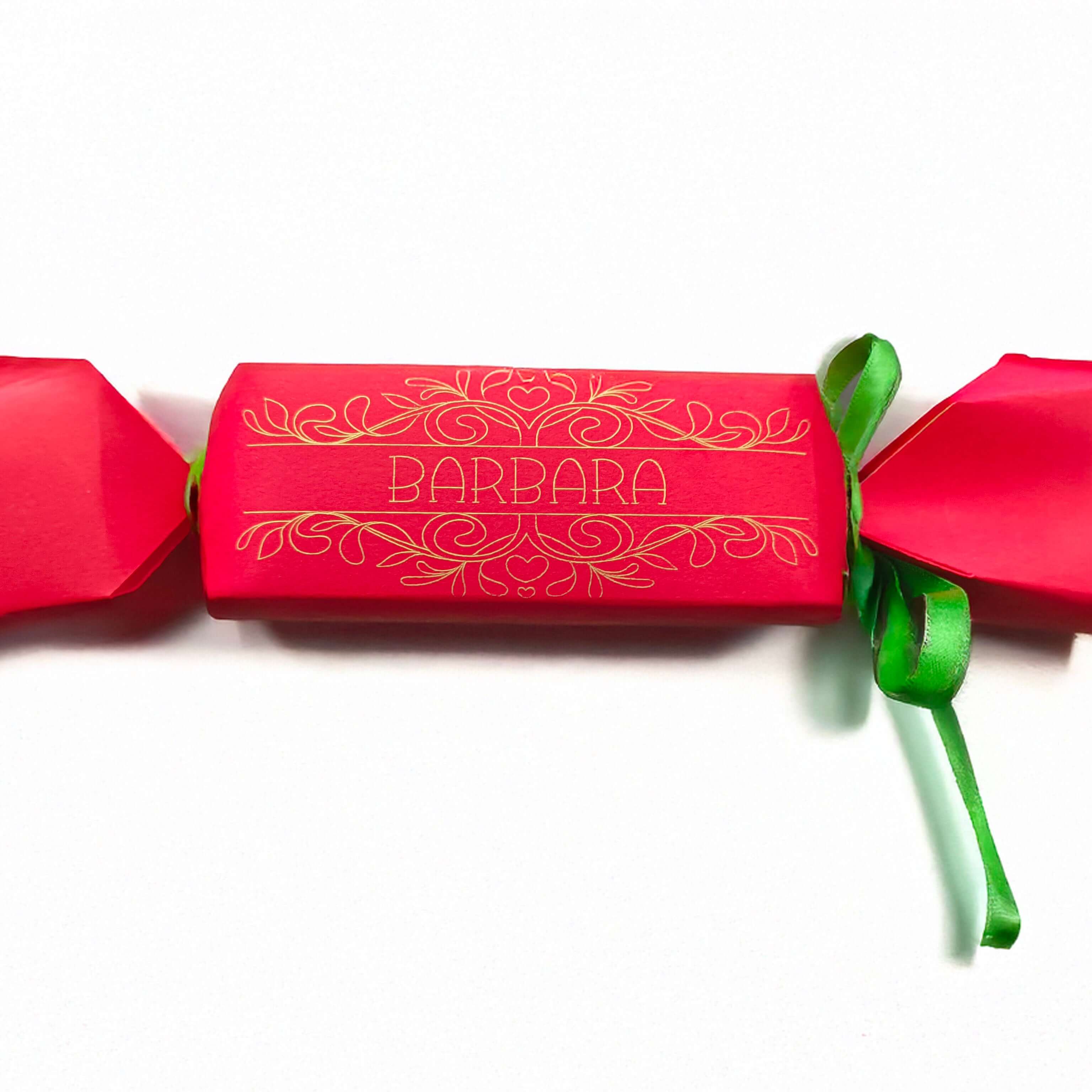Red cracker with gold foil design and personalised name “Barbara,” finished with green ribbon, photographed on a white background for product display.

