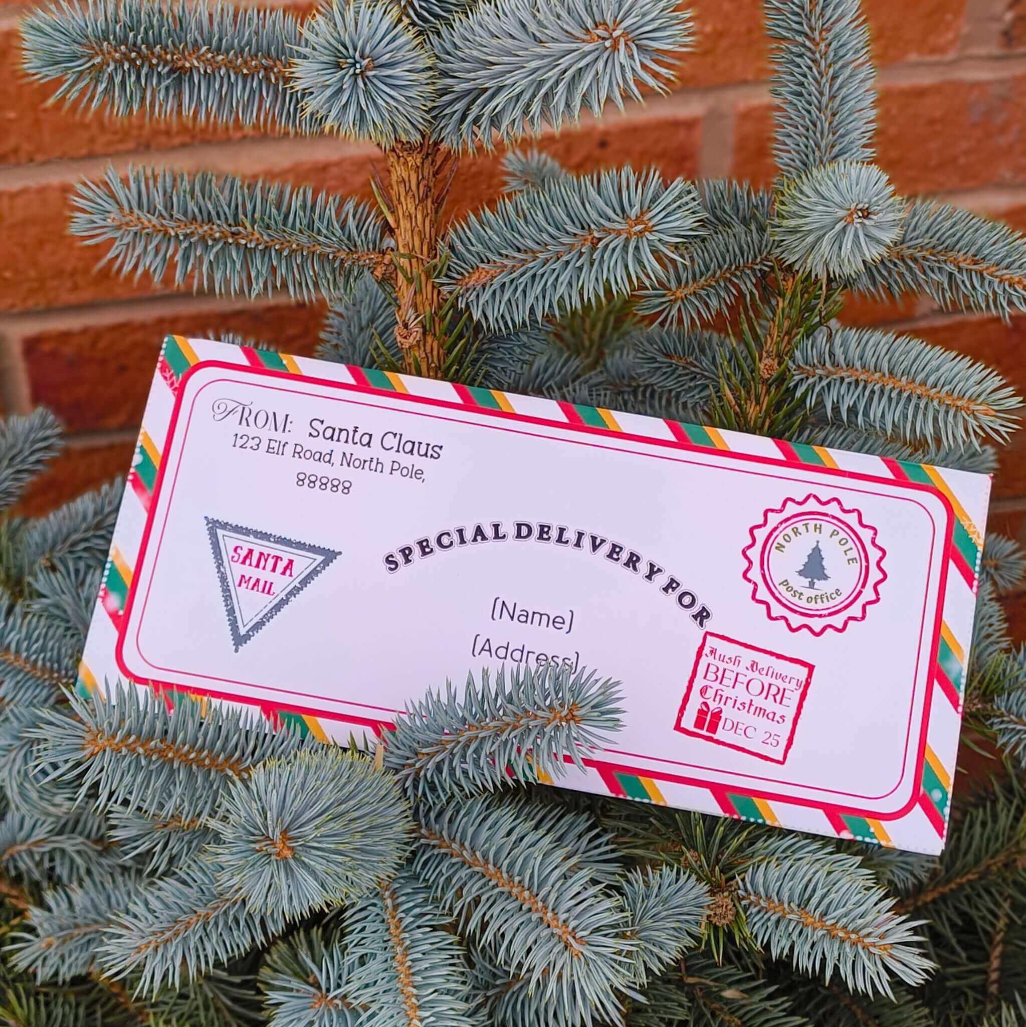 Personalised Santa delivery envelope resting on a Christmas tree with festive decorations and Santa's address.