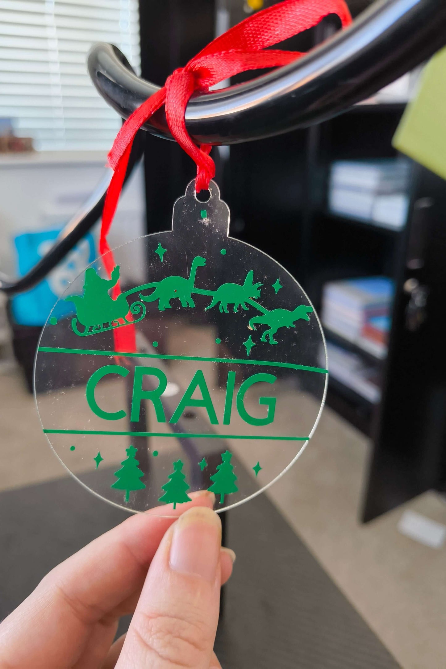 Clear acrylic dinosaur Christmas bauble with green vinyl, personalised with the name Craig, Santa in sleigh pulled by dinosaurs.