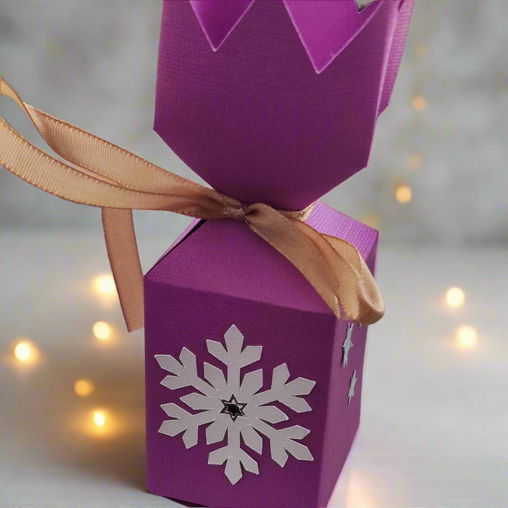 Handmade pink Christmas cracker box with snowflake design and ribbon, perfect for festive decoration or gifts.