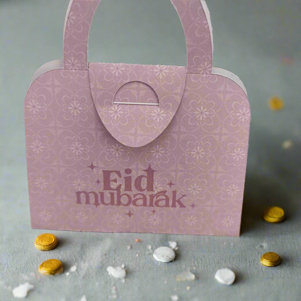 Light pink Eid Mubarak money holder with floral print, handbag design, surrounded by festive coins, perfect for Eid gifts.