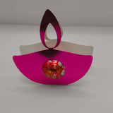 Pink metallic diya favour holding a chocolate, perfect for Diwali celebrations and party gifts.
