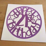 Purple papercut topper reading 'Happy 21st Birthday' in a circle design with stars, displayed on white card against a wooden background.