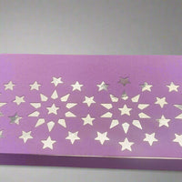 Close-up view of a handmade purple money holder featuring a silver foiled starburst pattern on textured cardstock, set against a soft grey background.