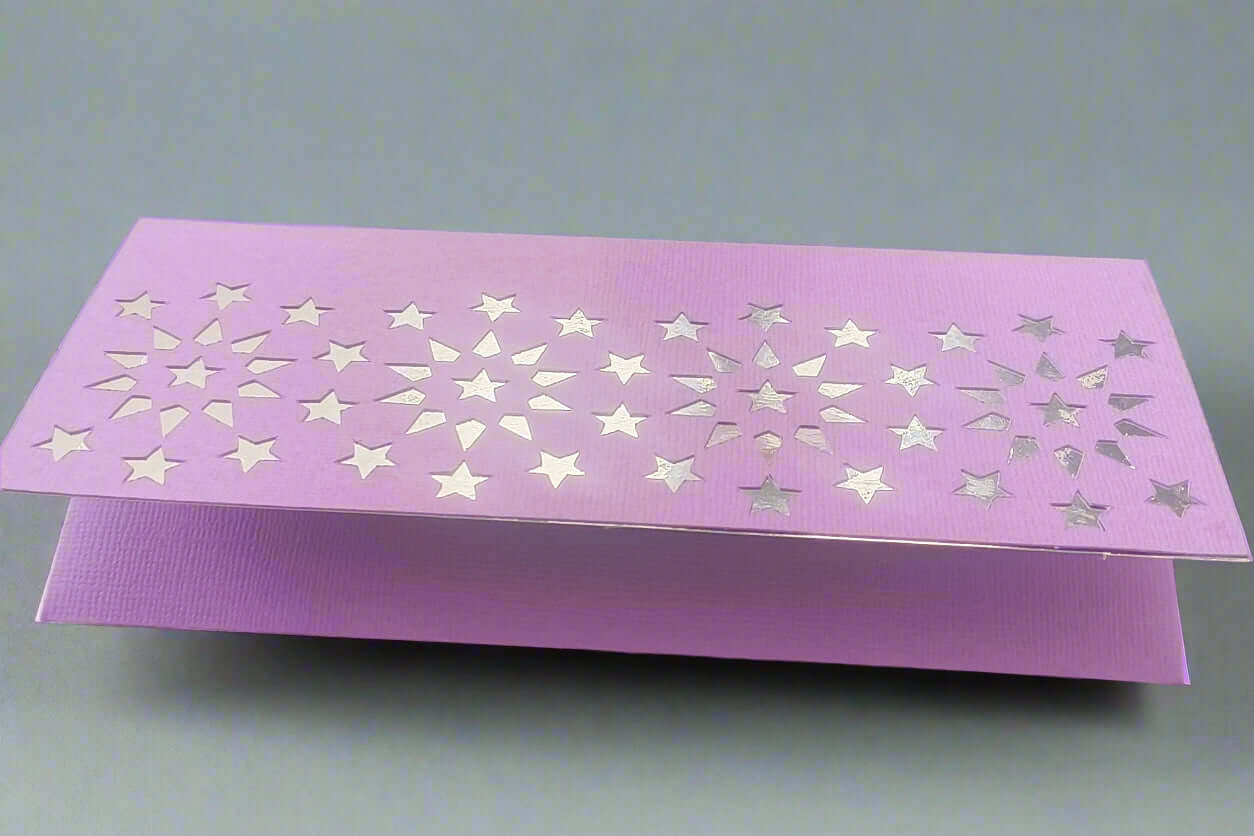 Handmade purple money holder crafted from textured cardstock, featuring a silver foiled starburst design, displayed on a soft grey background.