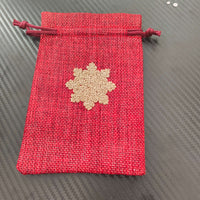 Red drawstring pouch gift bag featuring a golden snowflake, perfect for Christmas presents.