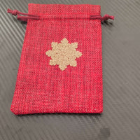Red drawstring pouch with golden snowflake design, perfect for Christmas gift wrapping.