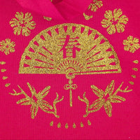 Close-up of a red tote bag with a gold glitter vinyl fan and floral design, showing intricate detail and texture.