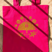Red tote bag with glitter gold vinyl fan and floral design, photographed outdoors in natural light.
